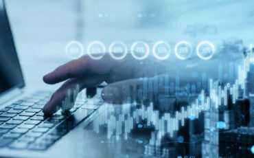 Close up of hand using laptop with creative candlestick forex chart or graph on blurry wide city background. Financial trade market and stock concept. Double exposure.