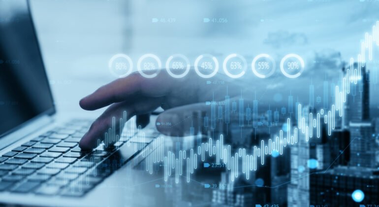 Close up of hand using laptop with creative candlestick forex chart or graph on blurry wide city background. Financial trade market and stock concept. Double exposure.