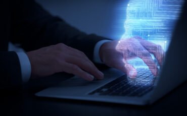 Man using modern laptop at black desk, closeup
