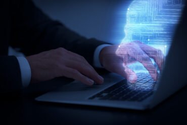 Man using modern laptop at black desk, closeup