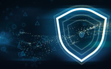 Creative wide perspective glowing shield hologram on blue wallpaper with various blurry icons. Cyber security, data protection concept. Modern wireframe design. 3D Rendering.